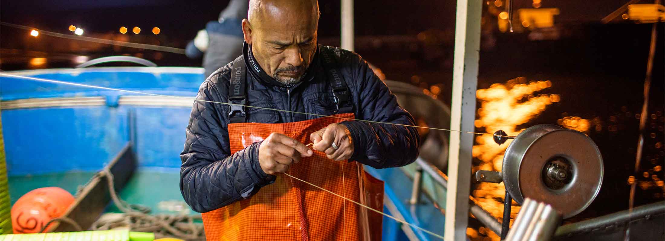 A worker on a mackerel boat untangles a fishing line